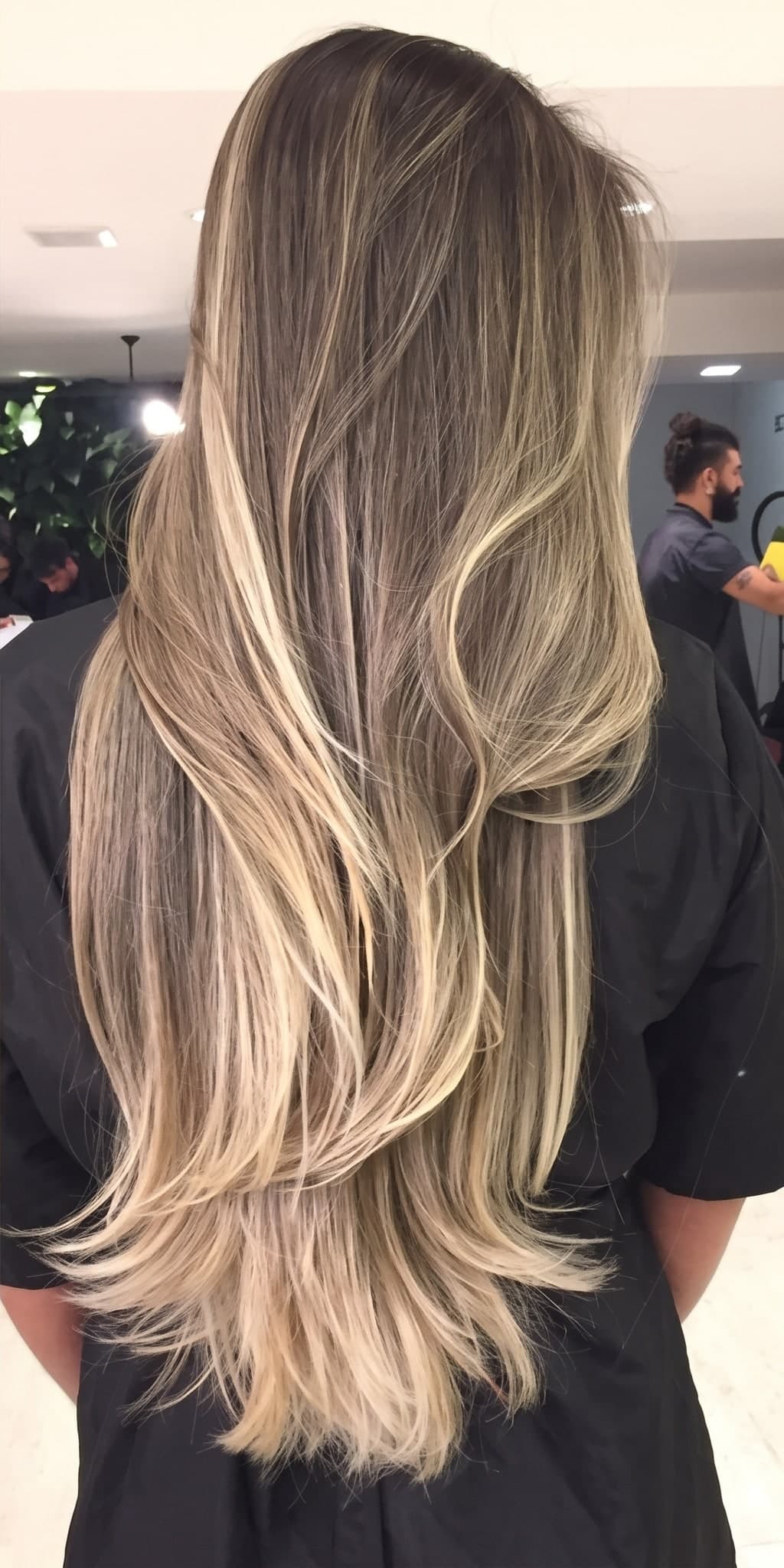 O mesmo cabelo depois do trabalho: longo e ondulado, loiro iluminado do meio às pontas, com a raiz mantida em tom escuro.